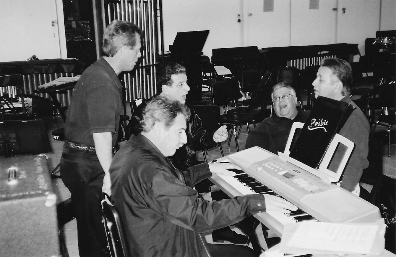 The Devotions in rehearsal around a keyboard